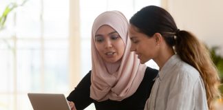 Focused muslim female mentor teacher teaching intern worker learning new skills